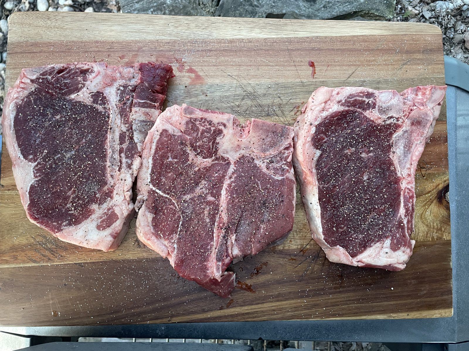 Thick-cut strip loin and T-bone steaks on a wood cutting board
