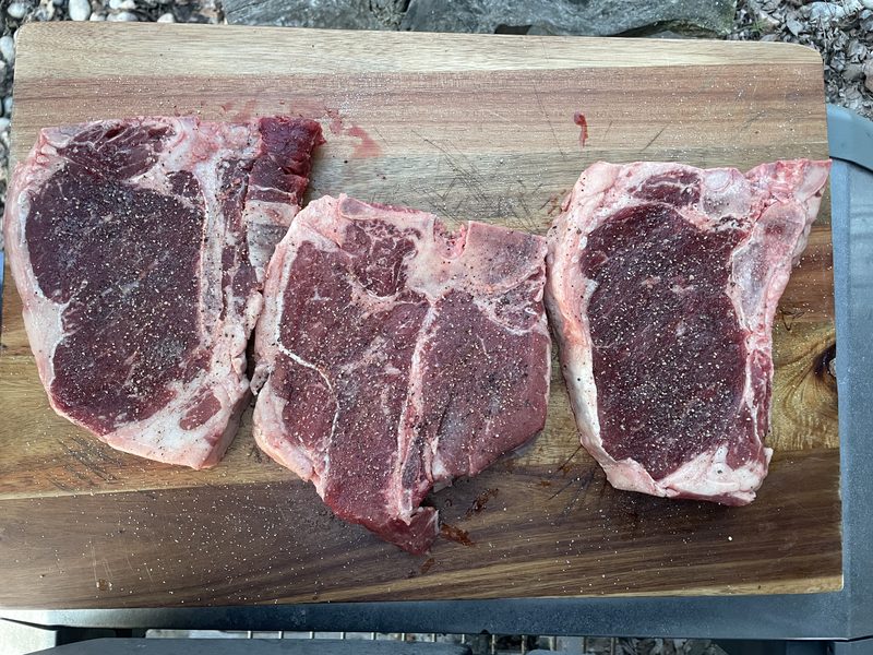 Thick-cut strip loin and T-bone steaks on a wood cutting board